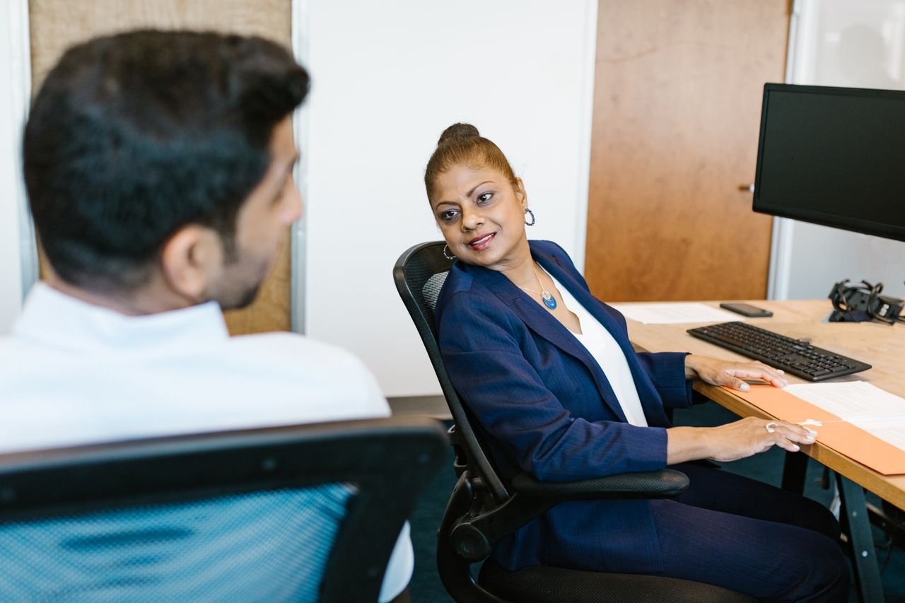 Portfolio Two colleagues engaged in conversation, showcasing communication in a modern office.